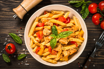 Pasta with chicken and vegetables at wooden table. Traditional italian food. Top view.