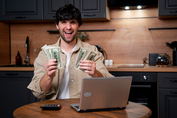A smiling businessman calculates the monetary income, holding dollar bills in his hands. A man uses a calculator while paying for utilities in the kitchen. 