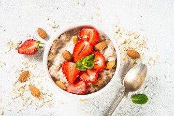 Fototapeta na wymiar Oatmeal porridge with fresh strawberry and nuts on white background. Healthy breakfast. Top view.