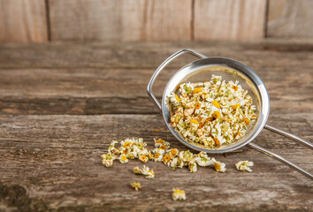 Dry chamomile flowers on a wooden table. Soothing chamomile tea. Herbal drink. flat layout. Space for text.Copy space.Medical prevention and immune concept. Folk alternative medicine.