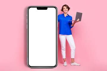 Full length photo cadre of young cheerful business woman wear formal clothes big touchscreen phone hold netbook isolated pink color background