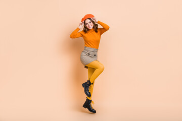 Full body portrait of cheerful nice lady jumping hands touch beret hat isolated on beige color background