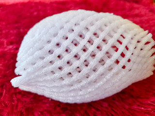 Close up of fruit protection foam net (Jaringan buah), isolated on red background.