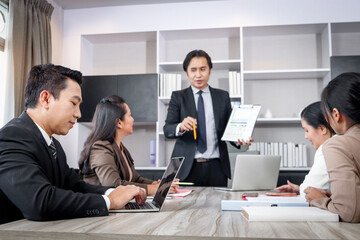 Businesspeople discussing at conference office desk, senior businessman typing on a laptop computer...