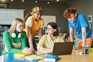 Group of students discussing online presentation with teacher in the classroom
