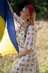Portrait of a girl holding the Ukrainian flag in the national Ukrainian costume.