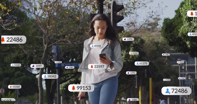 Animation of social media icons on asian woman with trolley bag using smartphone crossing the street
