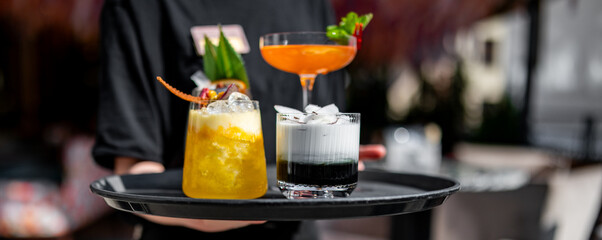 waiter with a tray of cocktails in a summer cafe