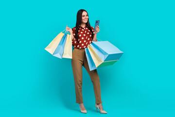 Full length photo of charming elegant person hold mall bags use smart phone isolated on teal color background