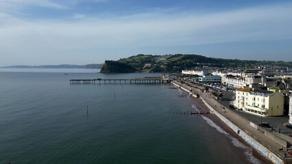 Fototapeta na wymiar Teignmouth, South Devon, England: DRONE VIEW: Teignmouth Promenade and and seafront properties; Teignmouth Pier and the Ness escarpment (behind the pier). Teignmouth is a popular UK holiday resort.