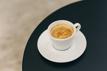 Cup of black coffee on a table in a street cafe.