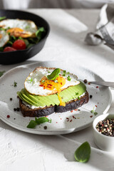 Breakfast wirh toast with avocado and eggs on a plate