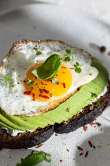 Toasted bread with avocado and fried egg for breakfast