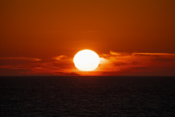 Big sun at sunset in the sea on the horizon.