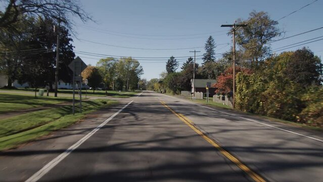 Drive along a typical street of an American town on a clear autumn day. Rear window view