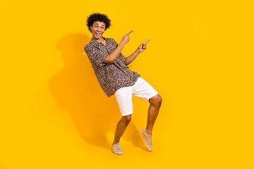 Full length photo of impressed crazy guy dressed leopard shirt indicating at summer sale empty space isolated on yellow color background
