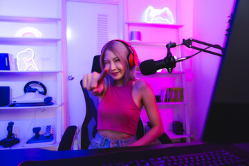 Fototapeta na wymiar Young Asian woman pro gamer have online live streaming, Pretty girl singing and chatting with her fans at home, Excited woman wearing headset to live streaming broadcast games challenge social media