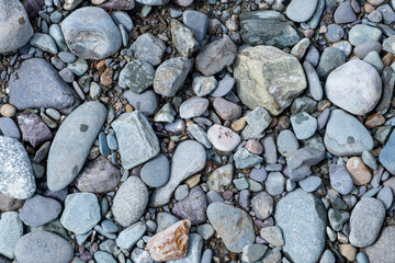 The stones were laid on the ground in the garden as a background. Background blur. Pebble stones background. Crushed stone on the seashore. Selective focus on object. 
