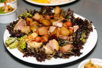 Duck breast salad with drunken pear, caramelized peach sauce on a white plate