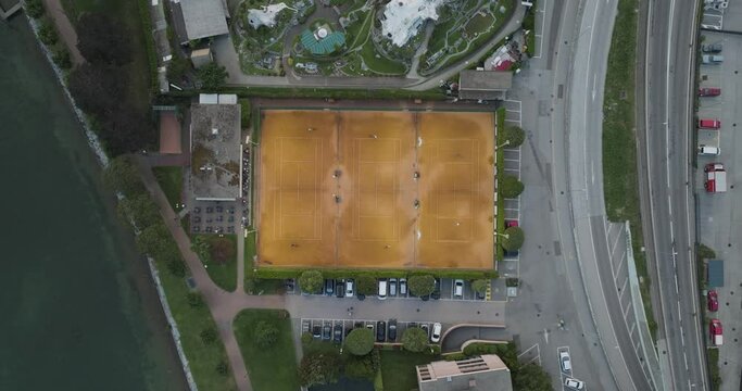 Aerial view of people playing tennis in a tennis club court along Lugano lake, Melide, Ticino, Switzerland.