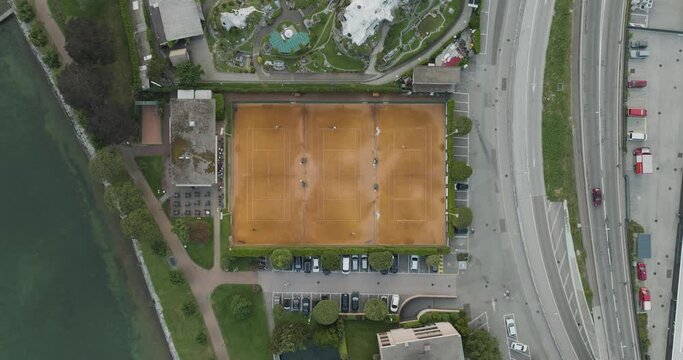Aerial view of people playing tennis in a tennis club court along Lugano lake, Melide, Ticino, Switzerland.