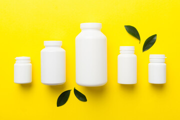 supplement pills with medicine bottle health care and medical top view. Vitamin tablets. Top view mockup bottle for pills and vitamins with green leaves, natural organic bio supplement, copy space