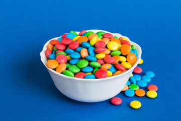 Multicolored candies in a bowl on a colored background. birthday and holiday concept. Top view with copy space