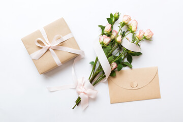 Greeting card mockup with copy space, pink ribbon and roses flowers on colored table background....