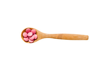 Vitamin capsules in a spoon on a colored background. Pills served as a healthy meal. Red soft gel vitamin supplement capsules on spoon