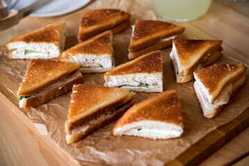 Sandwiches with cheese, chicken meat and cucumber on a wooden tray. Catering sandwich display.