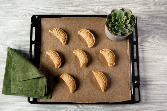 Azerbaijani pastries - traditional Shakerbura on a baking sheet on a tray and wooden background, top view