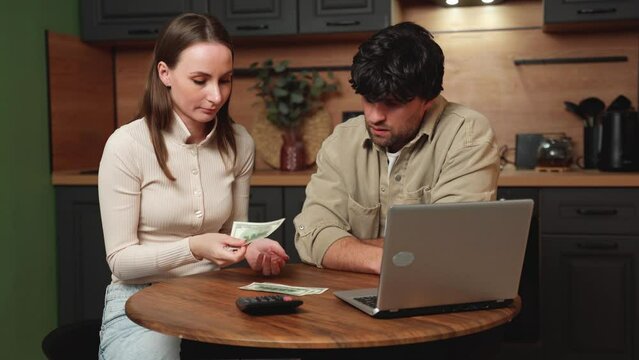 Financial stress, a young couple is sitting at the kitchen table experiencing stress and embarrassment due to the calculation of invoice expenses, lack of money to pay, mortgage or loan