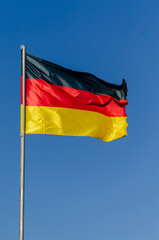 Germany's flag fluttering in the wind on a blue sky day.