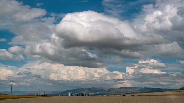 Clouds rolling over farm landscape in northern Utah viewing silos and grain bins.
