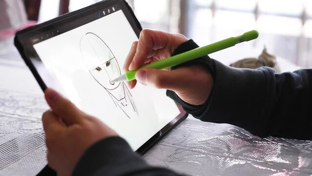 Hand holds tablet on white background and another hand with therapeutic wrist brace draws with digital pen, horizontal video