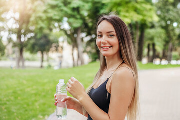 Happy smiling girl went for a run in the park with a bottle of water.