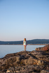 Girl stands at edge of lake at sunrise, Lake Superior