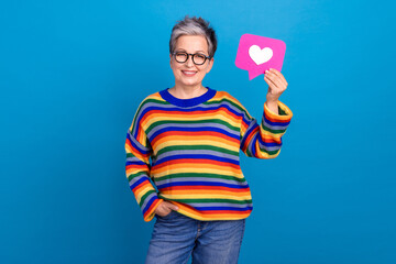 Photo of cheerful aged person toothy smile hand hold paper like notification card isolated on blue color background