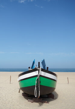 Traditional fishing boat painted in green and black on the beach of Nazaré, Portugal. vertical photo