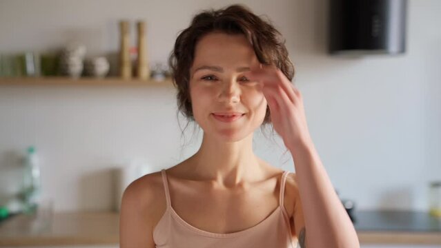 Young smiling beautiful woman pretty face looking at camera posing alone at home standing in kitchen. Girl with clean, healthy, glowing skin. Happy millennial caucasian girl close up front portrait