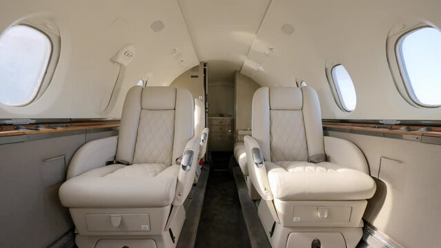 Luxurious interior of private business airplane with five beige leather seats and couch. Modern jet with state-of-art amenities to meet needs of high-profile people
