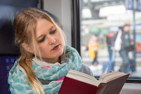 Junge Frau im Zug liest ein Buch