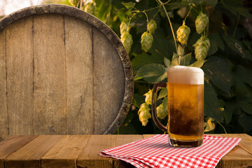 mug of beer, wheat ears, green hops and beer barrel on a wooden background. High quality photo