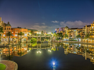 Fototapeta premium Century city canal side buildings lit up at night, Canal Walk, Cape Town, South Africa