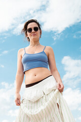 Beautiful young brunette in sunglasses against the sky