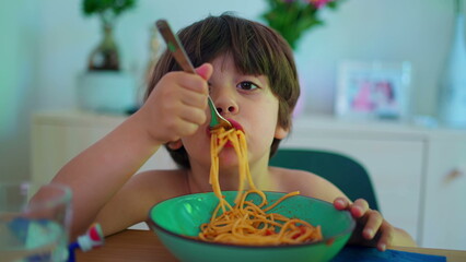Child eating spaghetti for lunch, close-up of small boy eats noodles during meal time - obrazy, fototapety, plakaty