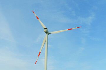 Wind turbine for power generation outdoors with sun and blue sky.