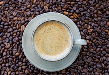 Cup with coffe on the roasted coffe beans.