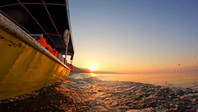 View from below along the orange sunset water of Shkoder Lake in Shiroka from a tourist boat. Albania