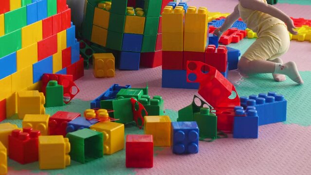 a little girl of 4-5 years old plays big blocks and builds a tower while in the children's playroom. children's entertainment for kindergarten age.